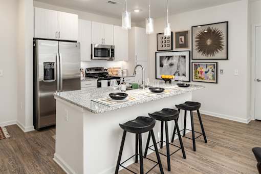 A kitchen with a white island and black stools.