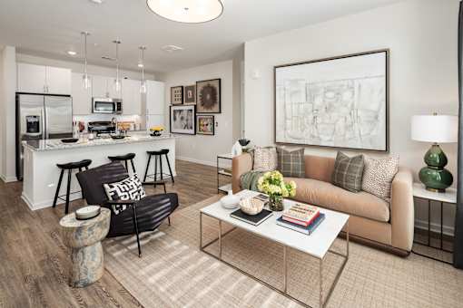 A modern living room with a kitchen area in the background.