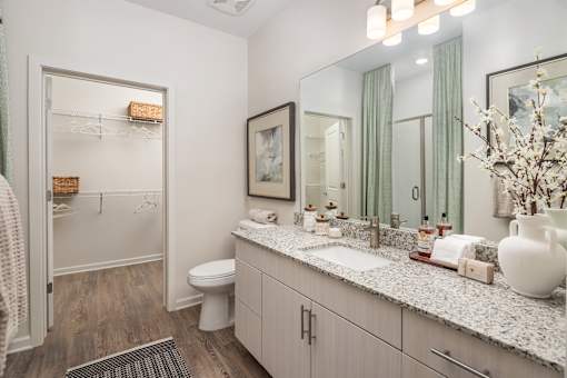 A bathroom with a toilet, sink, and mirror.
