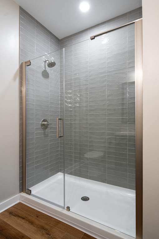A modern bathroom with a glass shower enclosure and a white bathtub.