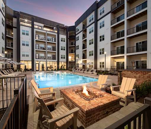 A fire pit sits in the middle of a patio surrounded by chairs.