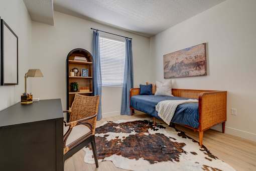A bedroom with a bed, chair, and rug.