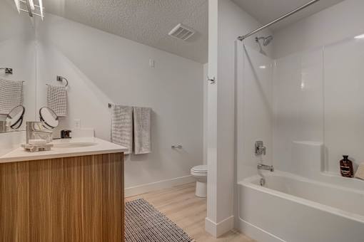 A white bathroom with a wooden vanity and a bathtub.