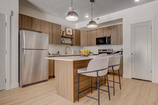 A kitchen with a refrigerator, stove, and bar stools.