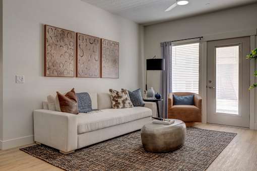 A living room with a white couch and a brown ottoman.