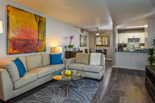 A living room with a grey couch, a coffee table, and a painting on the wall.