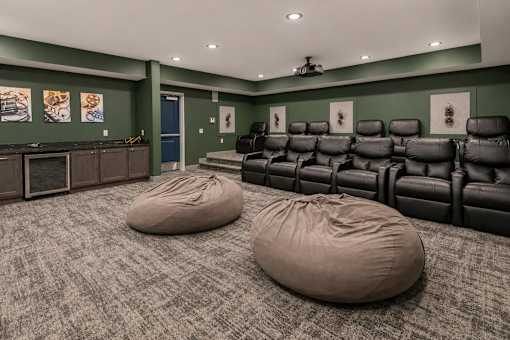 A room with a row of black leather chairs and two bean bag chairs in front of them.