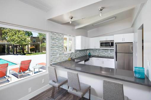 A kitchen with a pool outside the window.