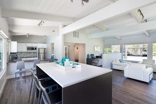 A modern kitchen with a white island and a dining table with chairs.