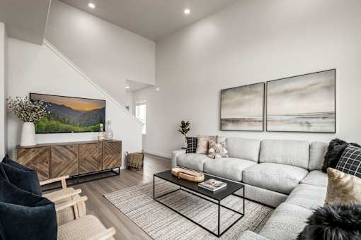 A living room with a grey sofa, a wooden cabinet, a glass coffee table and a painting on the wall.