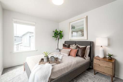 A bedroom with a bed, nightstand, and a window.