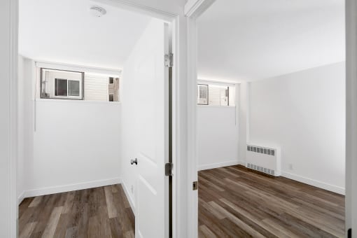 a bedroom with hardwood floors and white walls