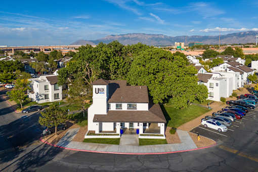 an aerial view of a large white house with a brown roof and a parking lot