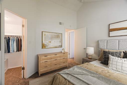 A bedroom with a bed, nightstand, and a painting on the wall.
