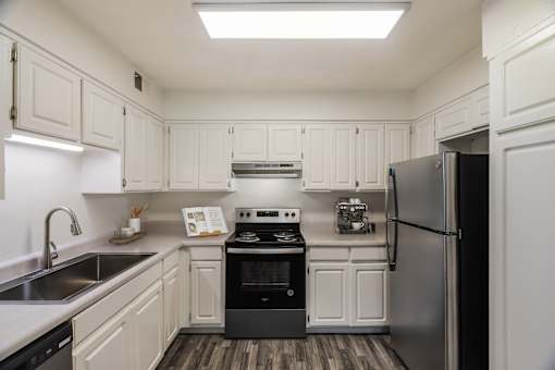 A kitchen with white cabinets and a black fridge.