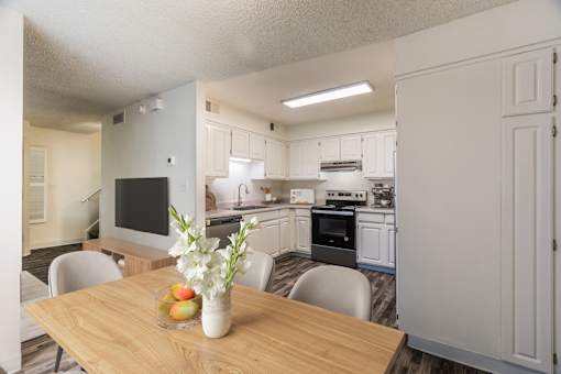 A kitchen with a table and chairs in front of it.