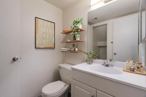 A bathroom with a toilet, sink, and mirror.
