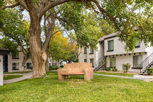 a stone bench sitting in the grass in front of houses