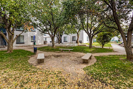 a park with benches and trees in front of a building
