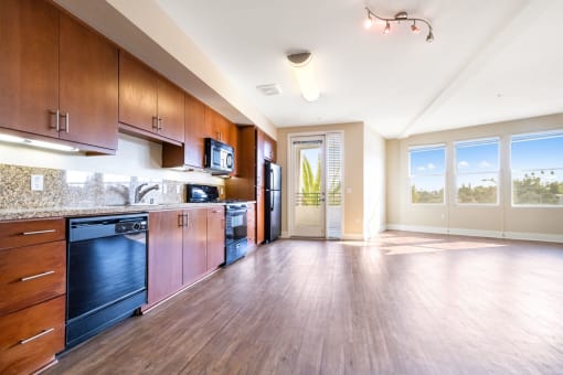 a kitchen and living room with wood floors and wood cabinets