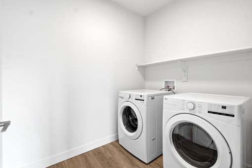 Two white front loading washing machines in a laundry room.