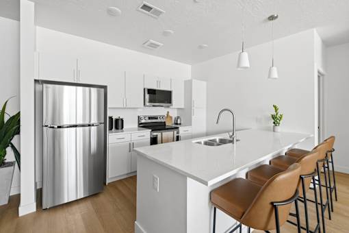 A modern kitchen with a stainless steel refrigerator and white countertops.