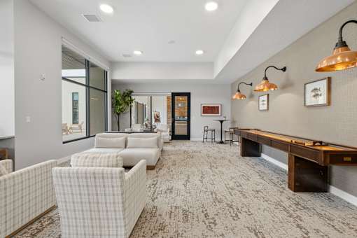 A living room with a long couch and a table with a lamp.