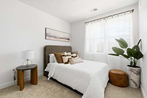 A bedroom with a bed, a side table, and a plant.