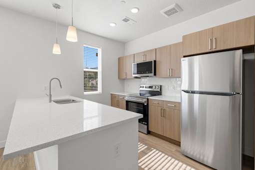 A modern kitchen with a white countertop and stainless steel appliances.