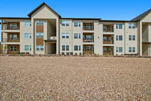 Apartment building with a gravel lot in front.