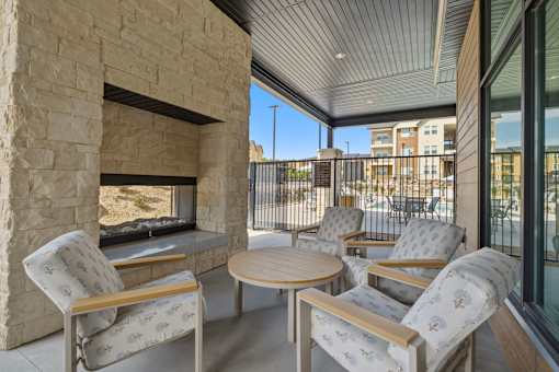 A patio with a stone fireplace and chairs.