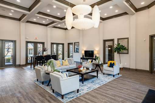 A large, well-lit living room with a central coffee table and a chandelier hanging from the ceiling.