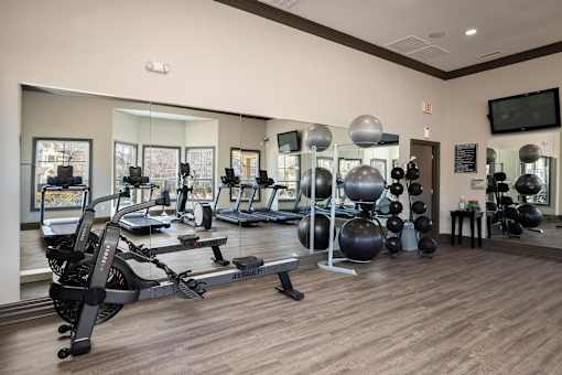 A gym with a variety of equipment including treadmills, exercise balls, and weights.