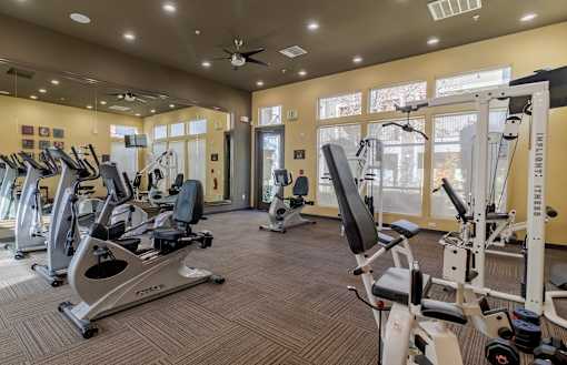 A gym with a variety of equipment including treadmills, stationary bikes, and weight machines.