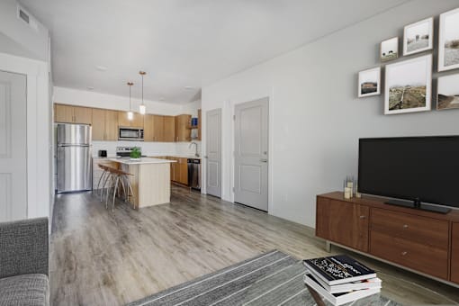 a living room with a tv and a kitchen with stainless steel appliances