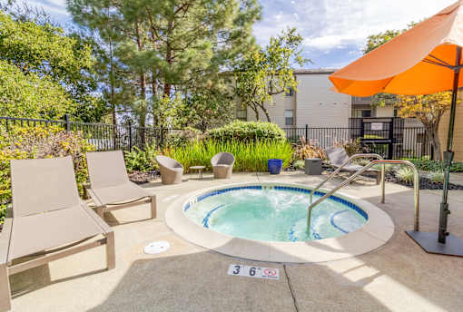A small pool surrounded by a concrete patio and a black fence.