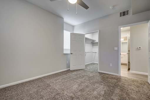 A spacious room with a carpeted floor and a ceiling fan.