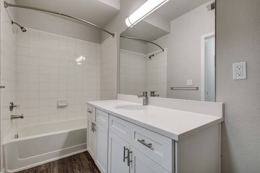 A white bathroom with a tub, sink, and mirror.