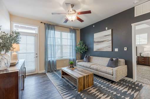 A living room with a beige couch, a wooden coffee table, and a ceiling fan.