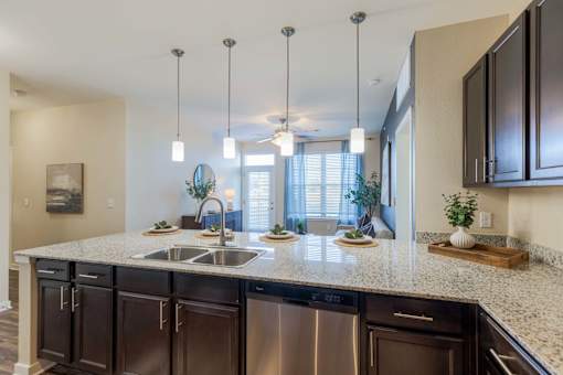 A kitchen with dark brown cabinets and a granite countertop.