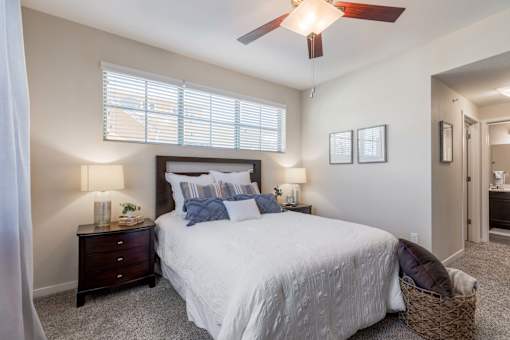 A bedroom with a bed, two nightstands with lamps, and a ceiling fan.