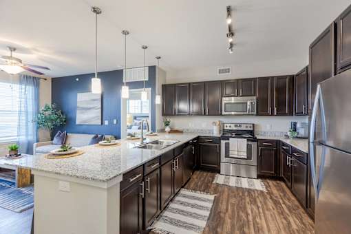 A modern kitchen with dark brown cabinets and stainless steel appliances.