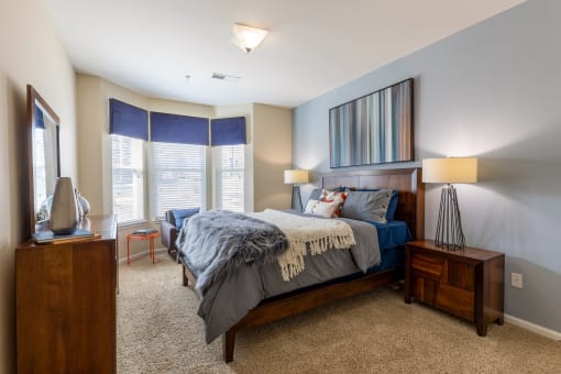 a bedroom with a large bed and two windows