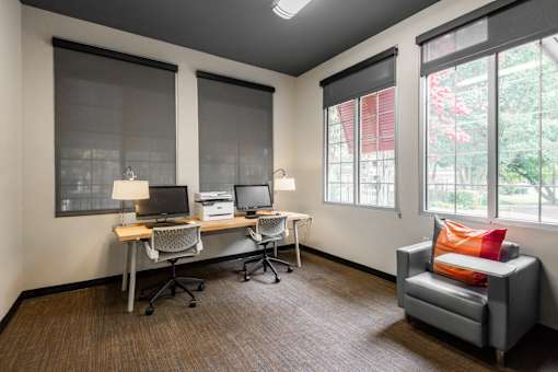 A room with a desk, chairs, and a couch.