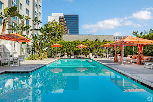 A swimming pool surrounded by orange umbrellas and lounge chairs.
