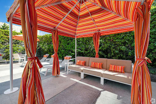 A patio with a striped canopy and a couch.
