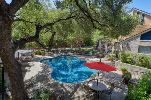 a backyard with a swimming pool and a patio with a table and chairs
