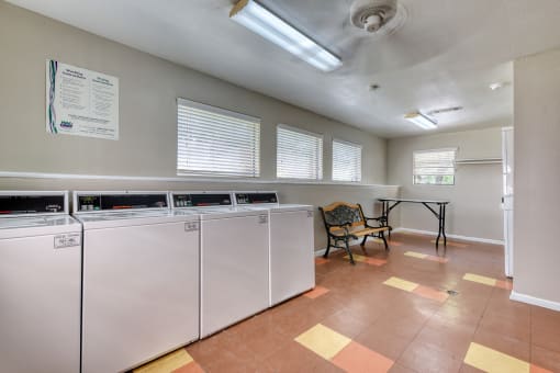 a laundry room with two washers and a table with a chair