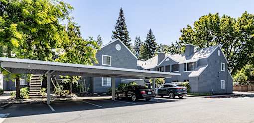 A house with a carport and two cars parked in front.