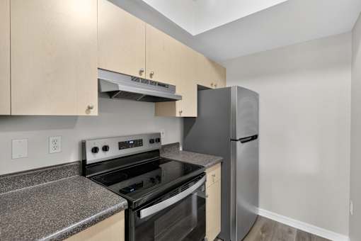 A kitchen with a black stove top oven and a stainless steel refrigerator.